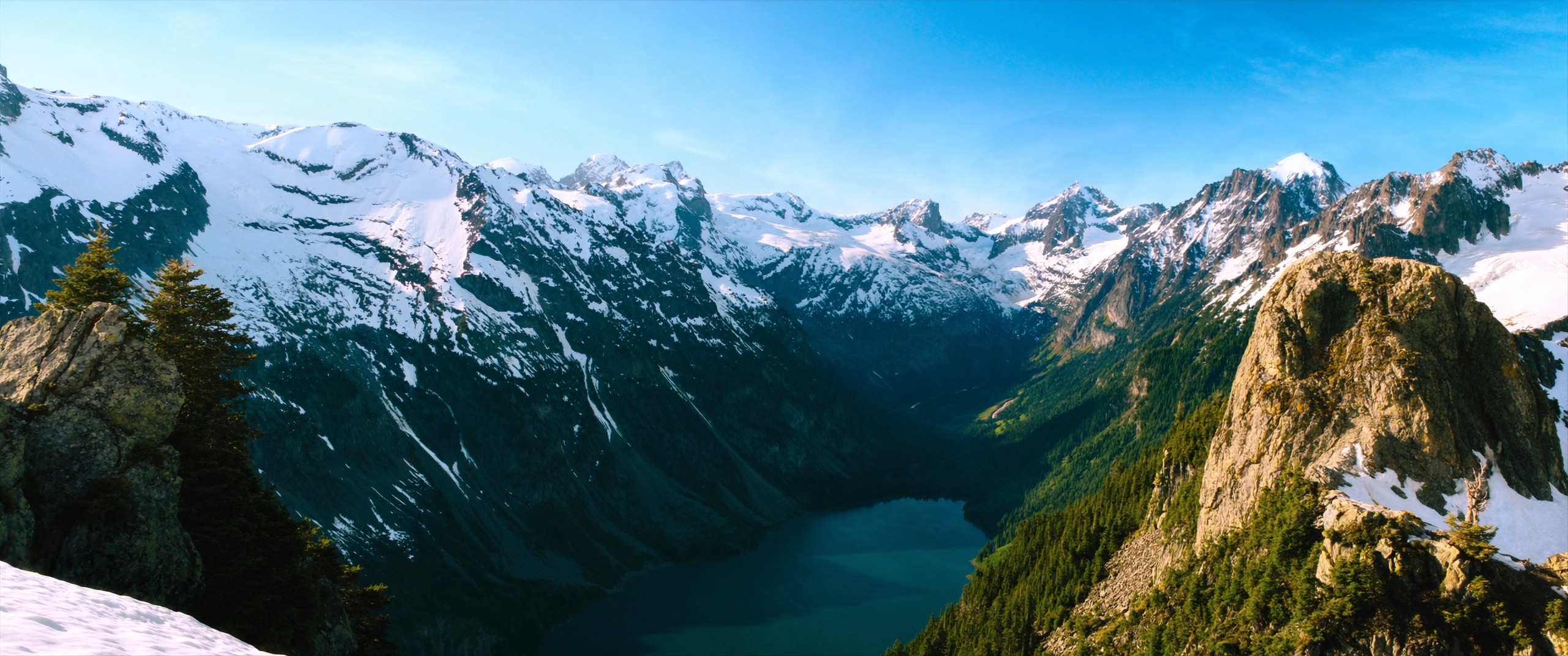 Snow-covered peaks surrounding a deep turquoise glacial lake in the North Cascades